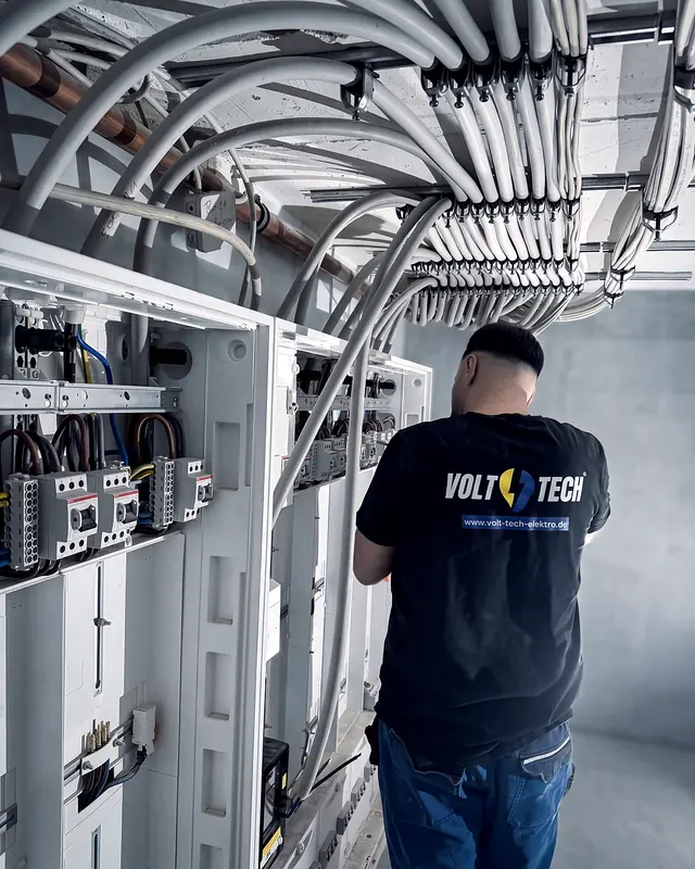 Volt Tech Monteur vor einer grossen Zählerschrank-Anlage mit Kabeltrassen im Rohbau